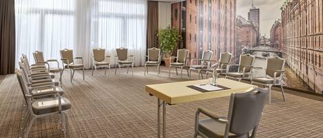 A conference room with a long table, multiple chairs, and a cityscape mural on the wall.
