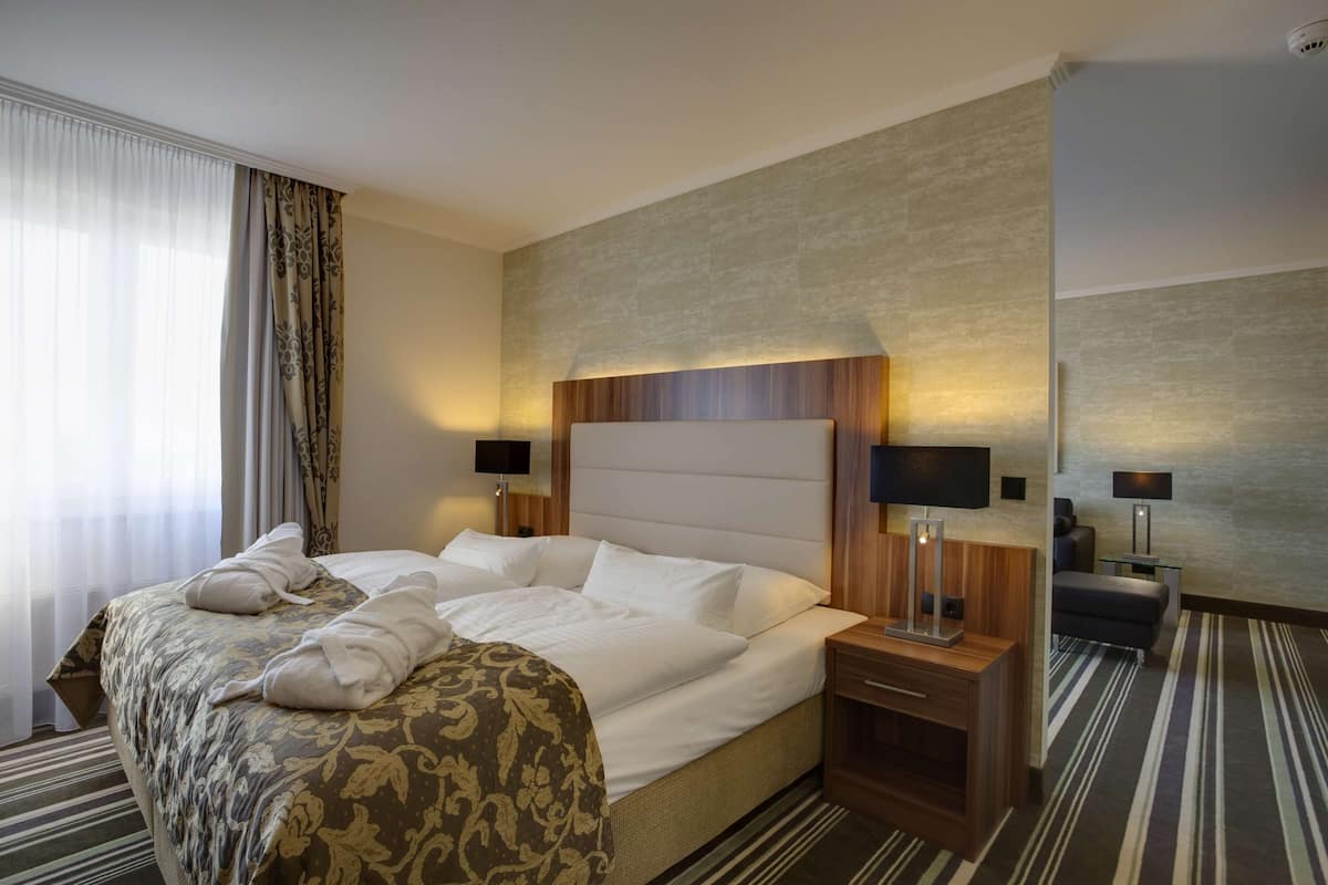 Quarto de hotel com uma cama grande, mesas de cabeceira, escrivaninha e uma cadeira.