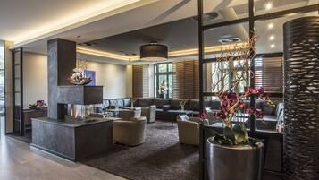 A modern interior with a fireplace, seating area, and large windows.