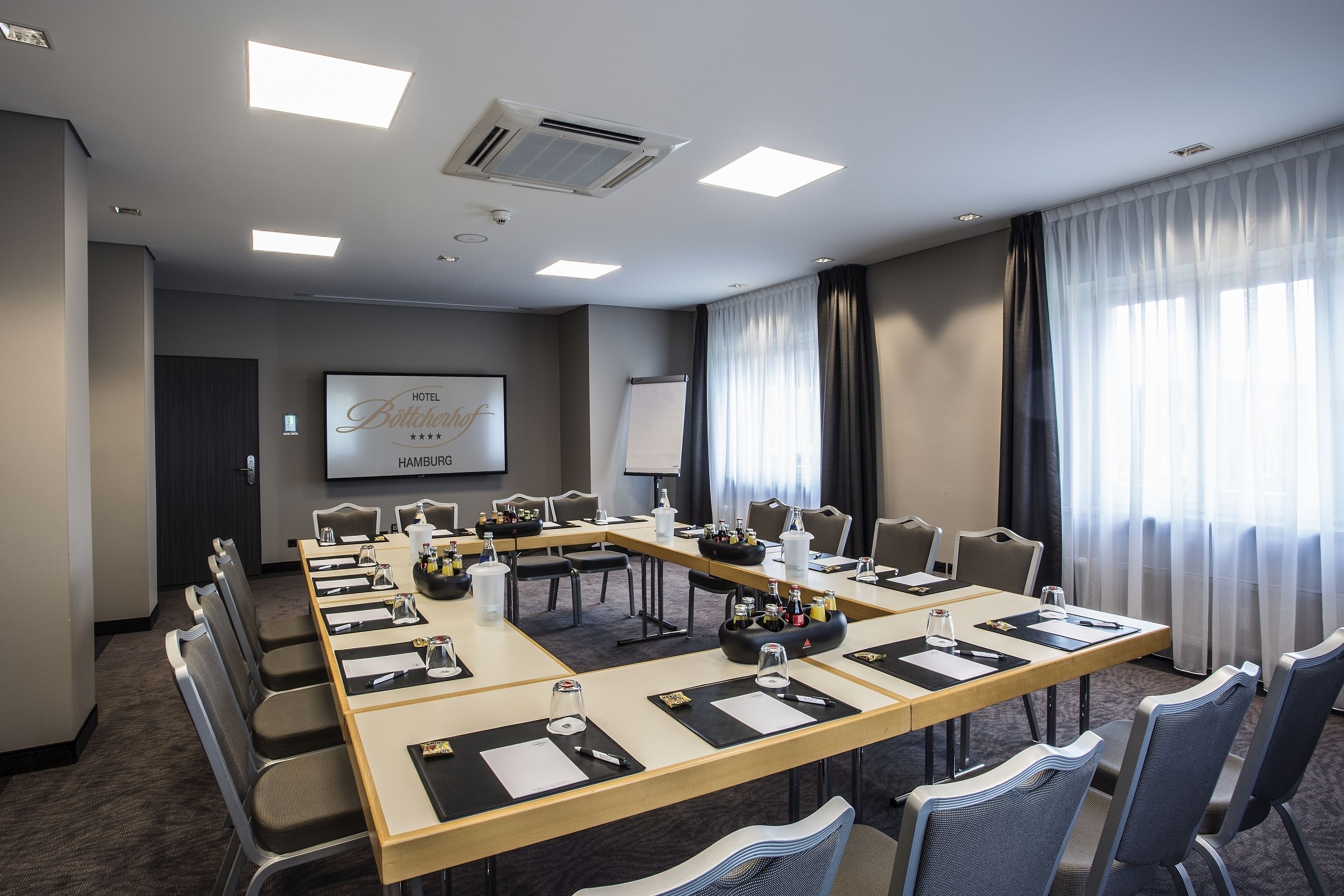 A conference room with a long table, chairs, a projector screen, and a whiteboard.