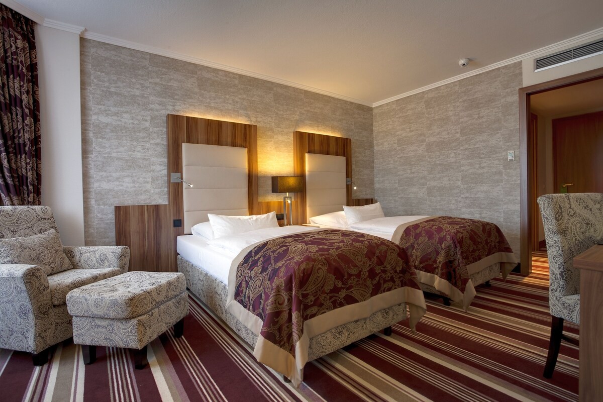 Une chambre d’hôtel avec deux lits, un canapé et un fauteuil.