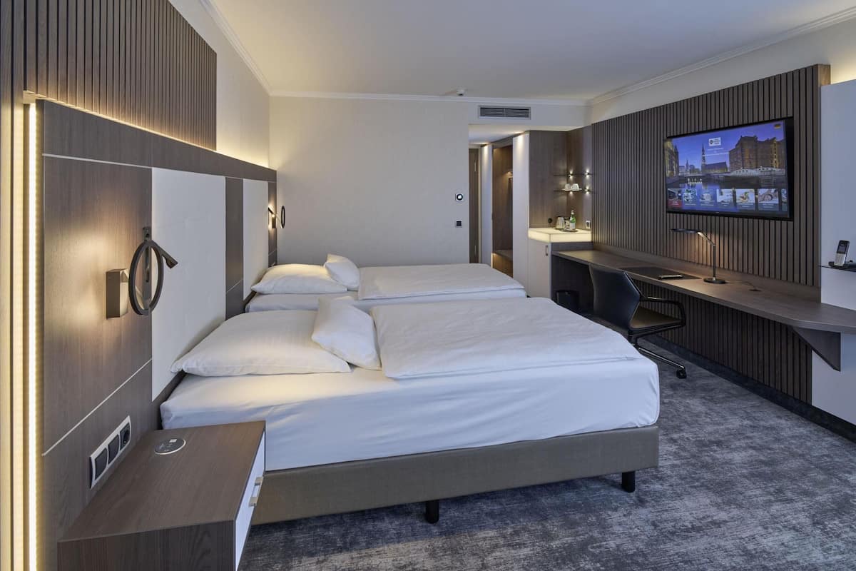 Quarto de hotel com uma cama grande, uma mesa, uma televisão e um banheiro.