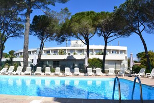 A swimming pool with white lounge chairs and a building with balconies in the background.