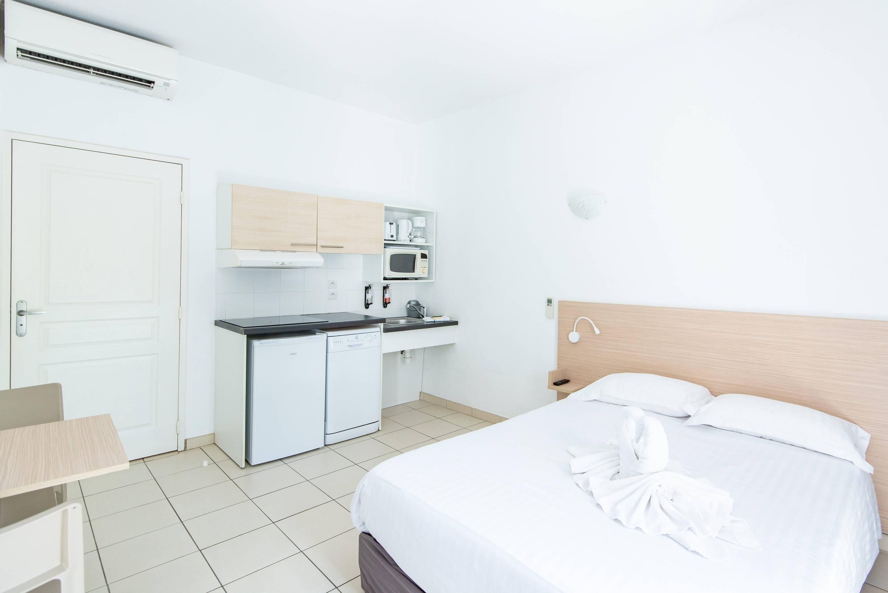 Une chambre d’hôtel comprenant un lit, un bureau, une kitchenette et une salle de bain.