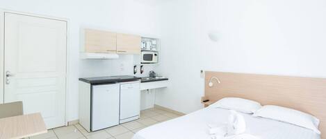 Habitación de hotel con cama, escritorio, kitchenette y baño.