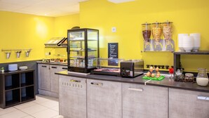 Una barra de desayuno con una máquina de café, una vitrina de vidrio y un menú en pizarra.