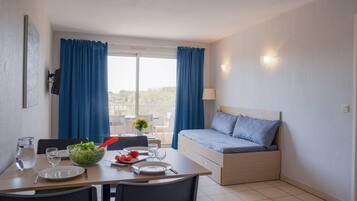 Una habitación compacta con cama, una mesa de comedor con sillas, un balcón pequeño y vistas al exterior.