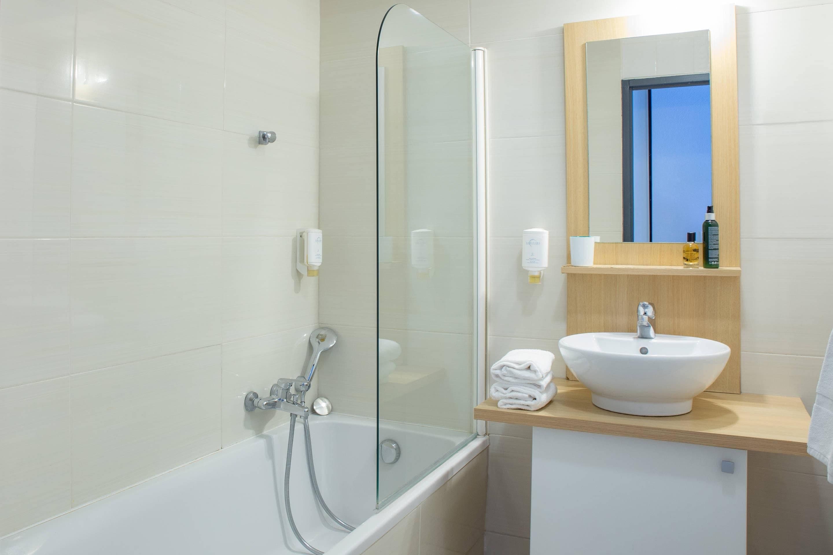 A modern bathroom with a glass-enclosed shower, a white sink, and a wooden vanity.
