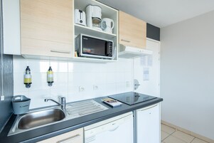 Una cocina moderna con microondas integrado, un lavamanos y una encimera con una revista.