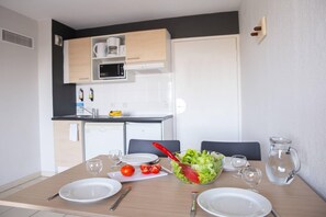 A dining table with plates, a pitcher, and a salad bowl. - Comfort Aparthotel Frejus La Tour De Mare (Fréjus)