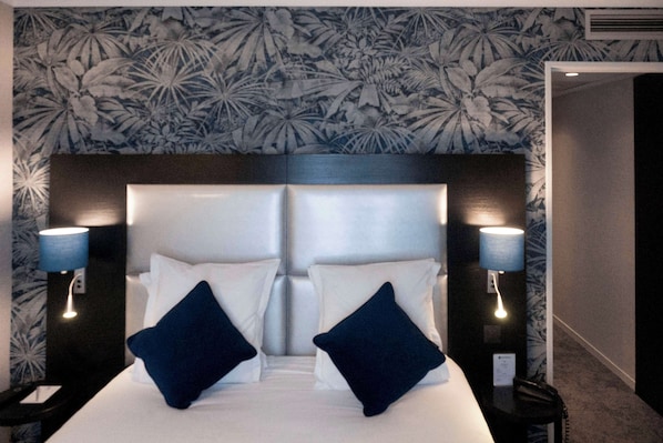 Una habitación de hotel con una cama grande, dos mesitas de noche y un cabecero con estampado floral.