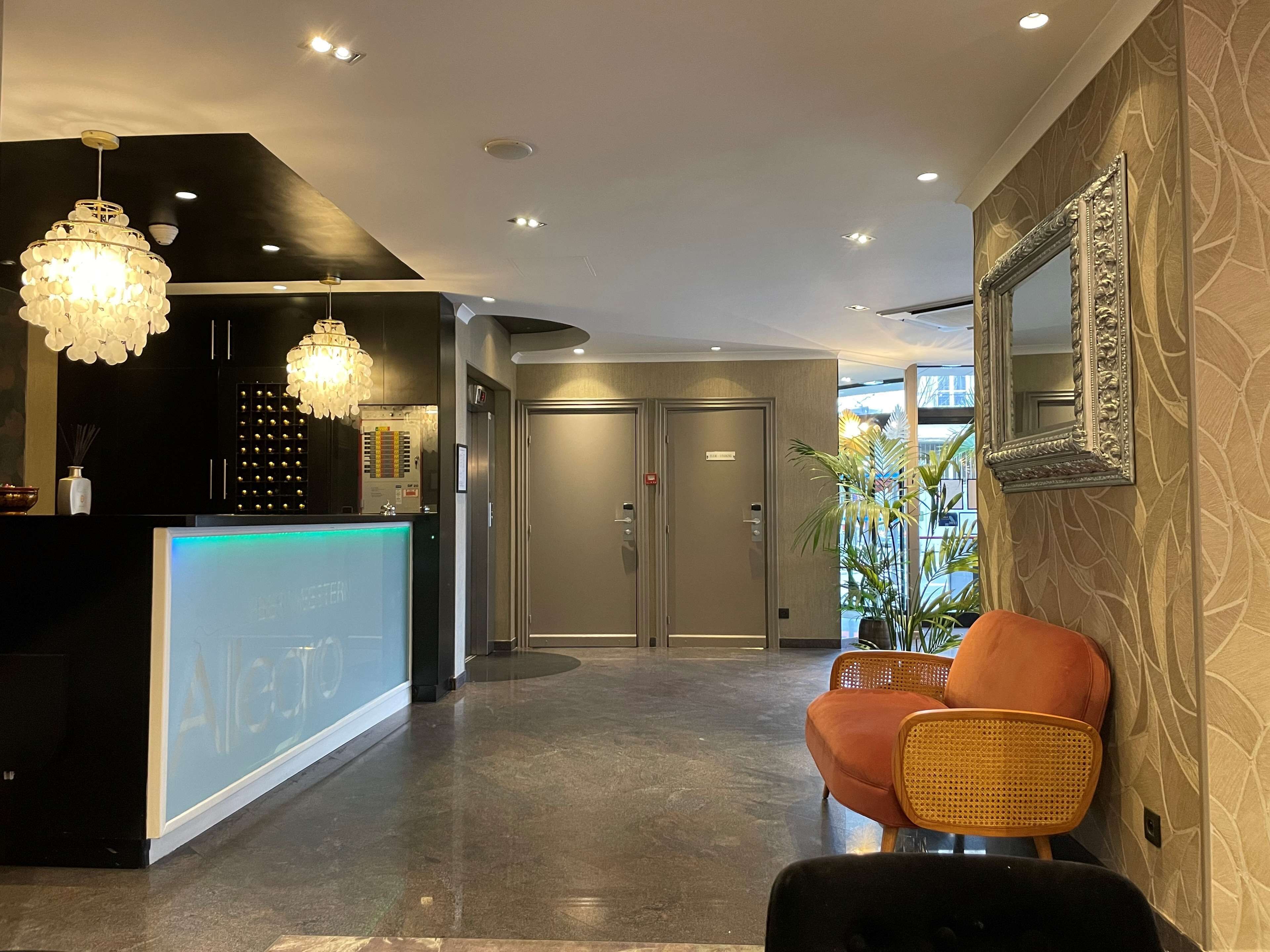 Vestíbulo de hotel con mostrador de recepción, dos puertas, un espejo y una zona de estar.