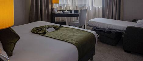 Una habitación de hotel con cama, escritorio, silla y un pequeño sofá.