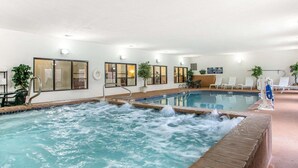 Piscina interior con bañera de hidromasaje, sillones de descanso y zona de recepción.