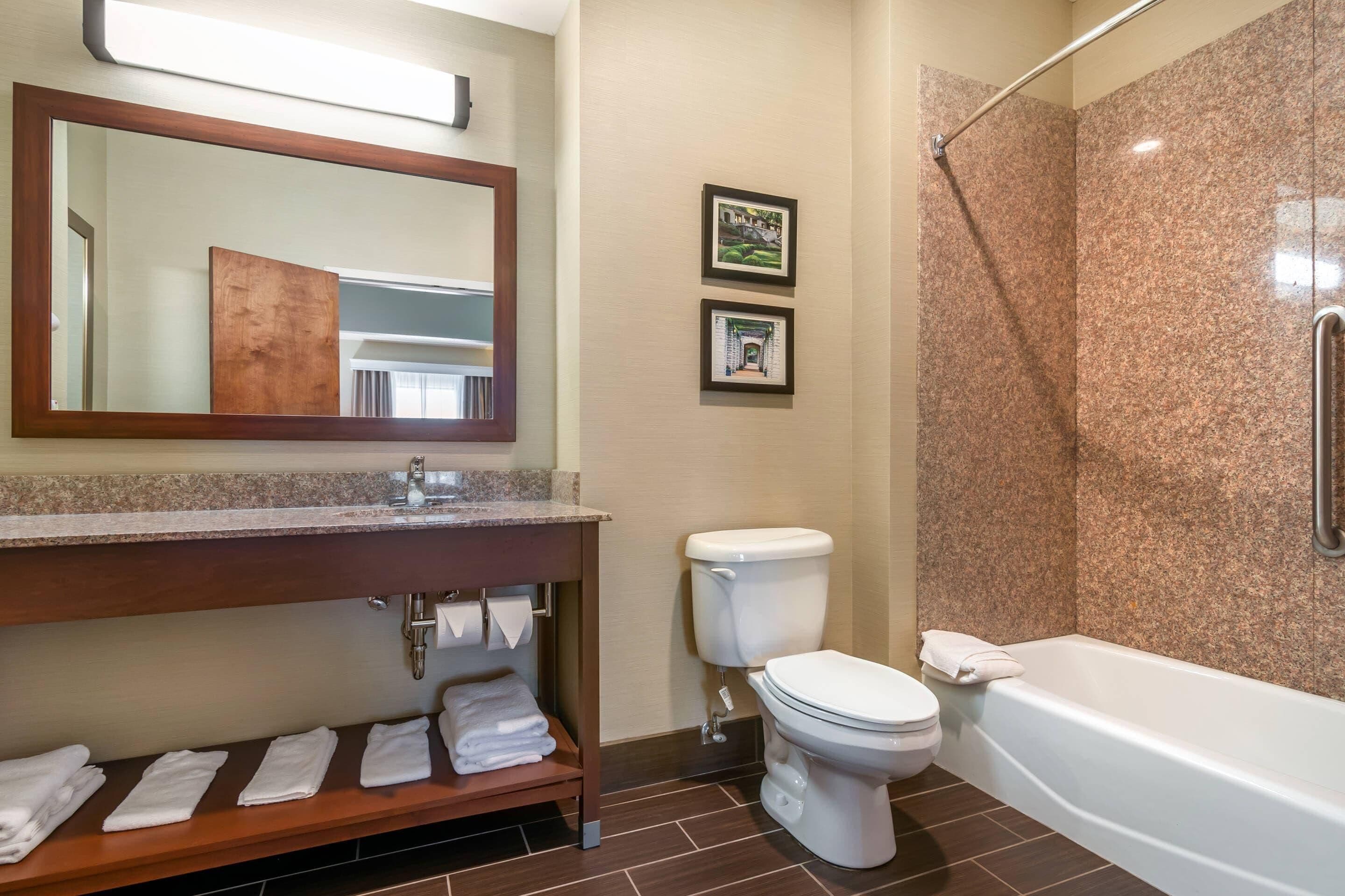 Un baño con lavabo, inodoro y bañera. Hay toallas en el mostrador y una cortina de ducha.