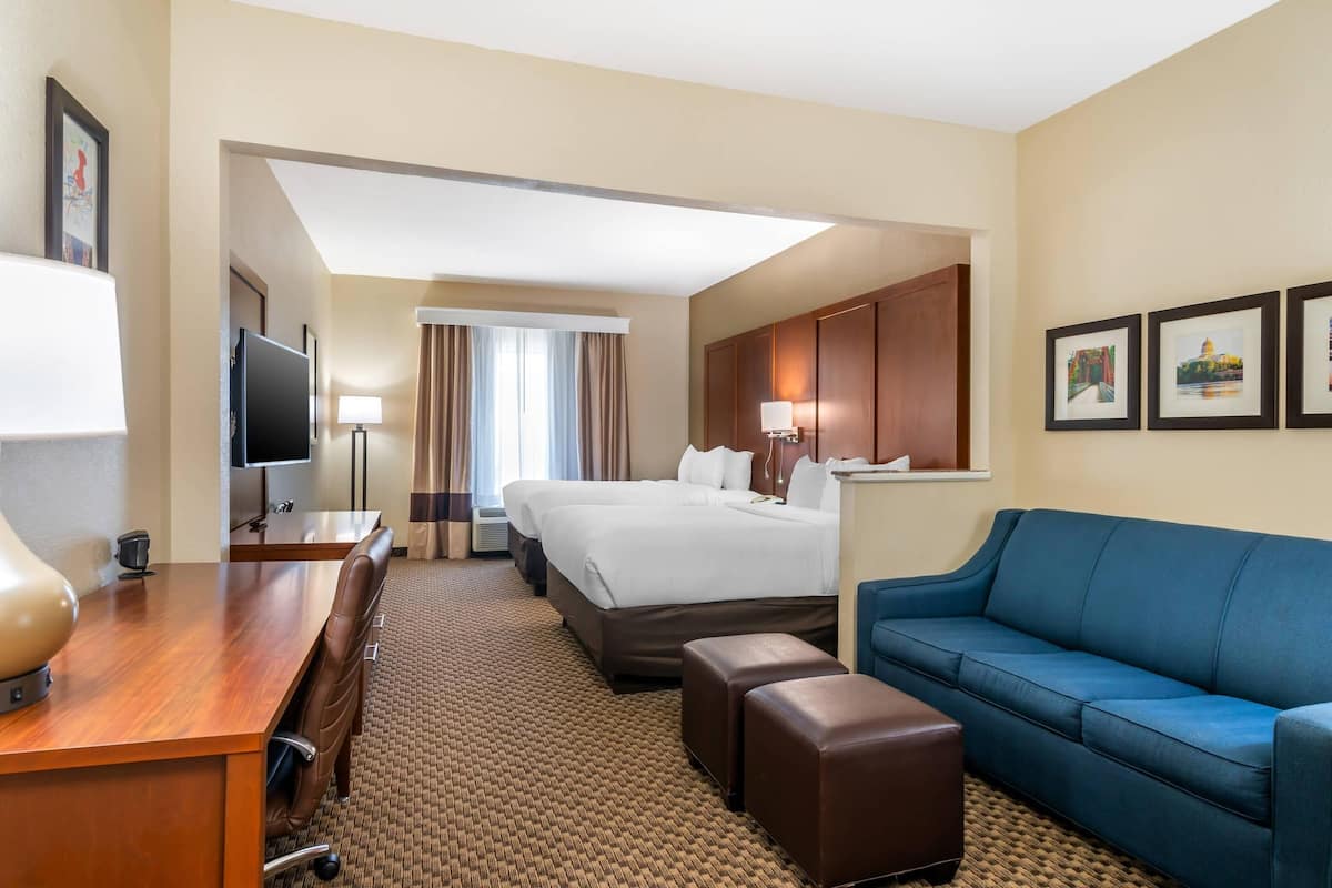 A hotel room with a bed, a desk, a blue sofa, and a TV.