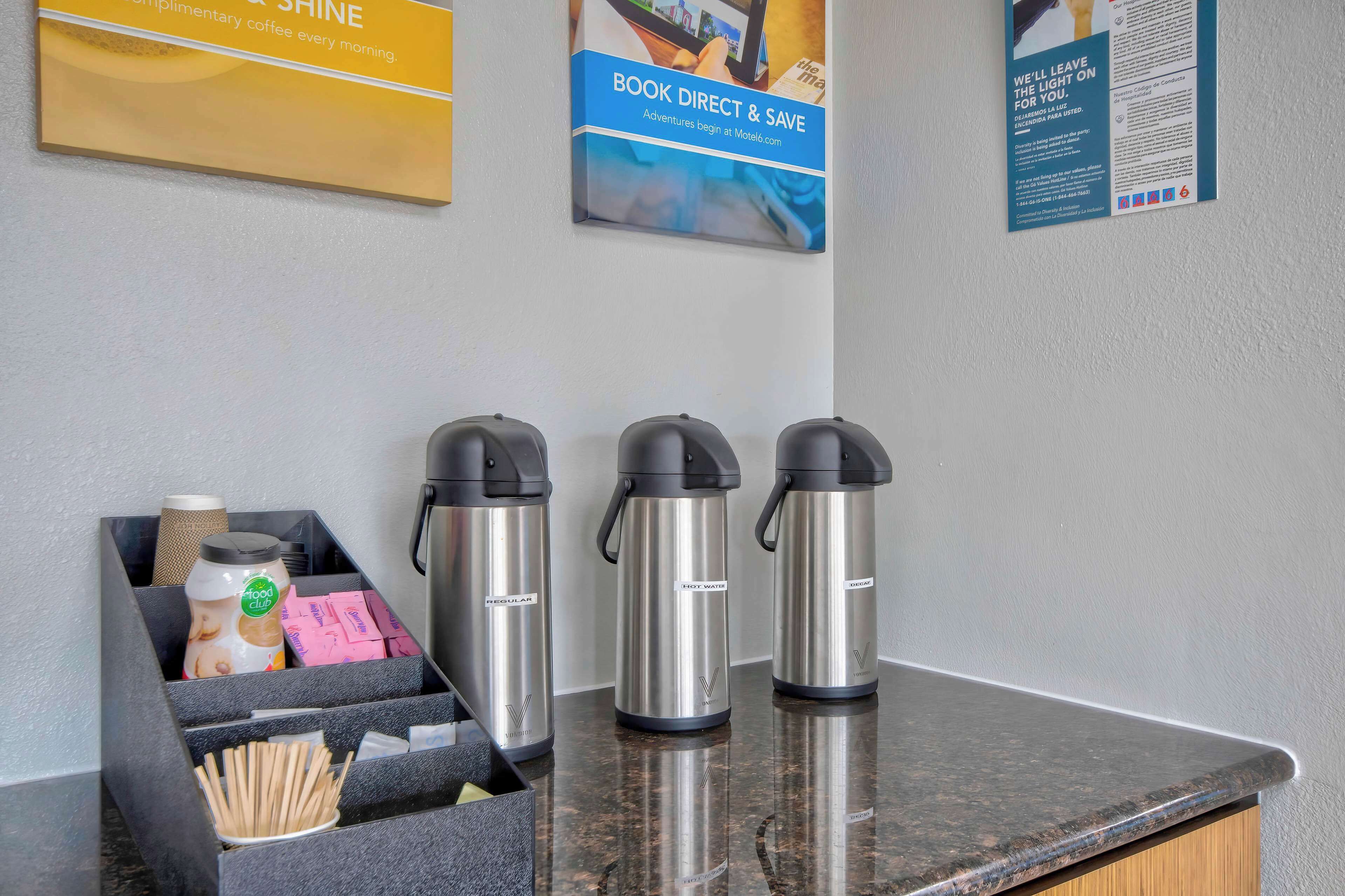 Una estación de café con tres máquinas de café eléctricas, un molinillo y un recipiente con utensilios.