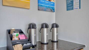 Una estación de café con tres máquinas de café eléctricas, un molinillo y un recipiente con utensilios.