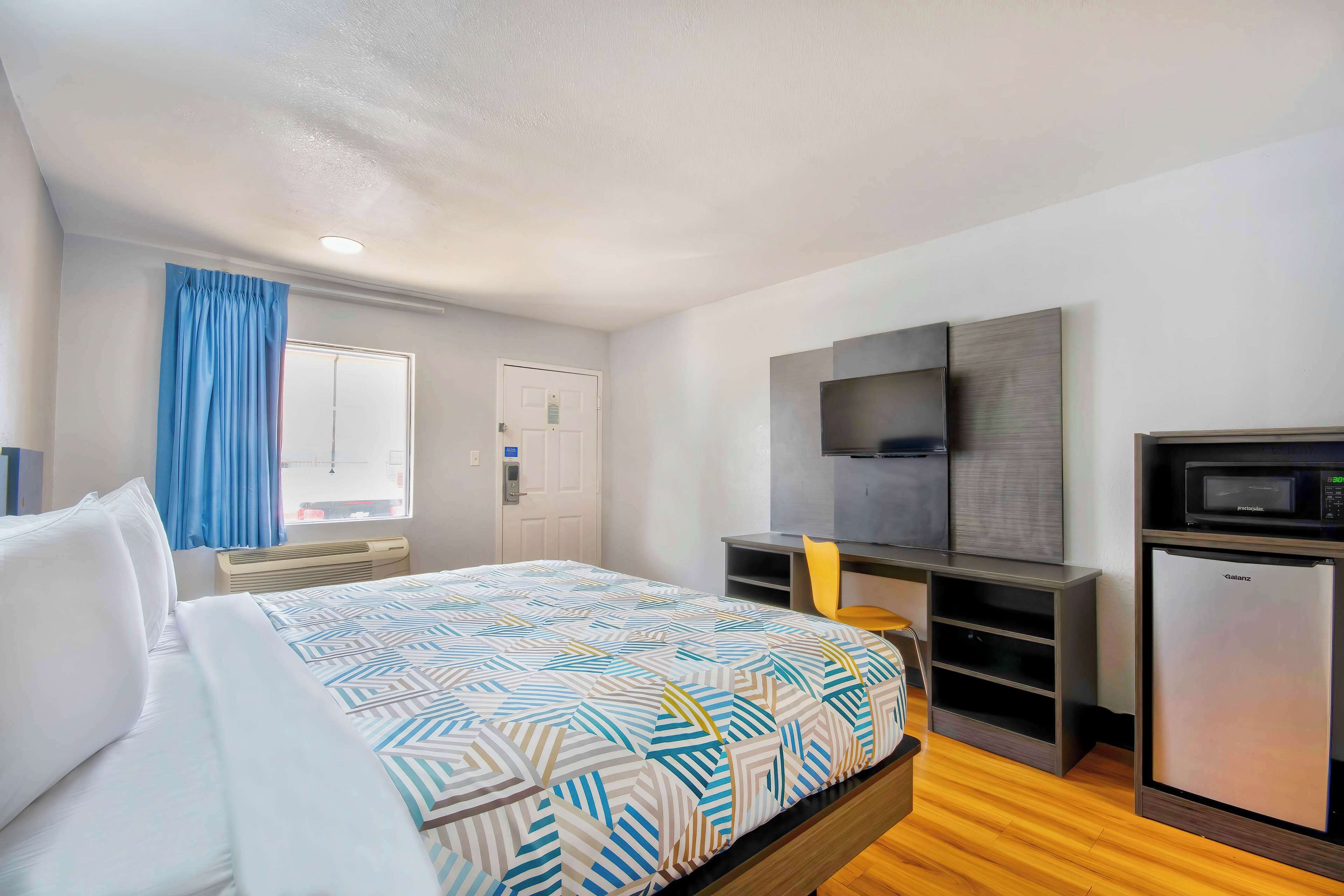 Een hotelkamer met een bed, een bureau, een televisie en een koelkast.