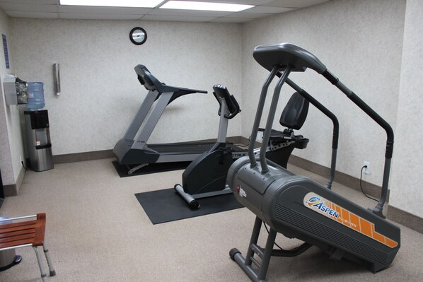 A gym with a treadmill, an elliptical, and a water cooler. - Navajo Nation Inn (Window Rock)