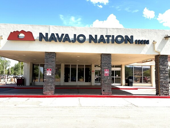 The exterior of Navajo Nation Inn with a clear entrance, stone pillars, and a no parking sign.