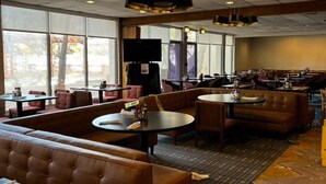 Een restaurant met zitbankjes, tafels en een groot raam.