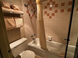 A bathroom with a bathtub, toilet, and a shower curtain.
