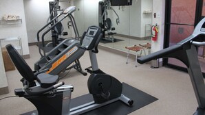 Een sportschool met cardioapparatuur, een spiegel en een brandblusser.