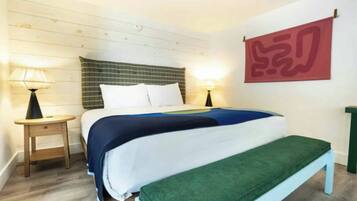 Un dormitorio con cama, mesitas de noche, un banco y una obra de arte colgada en la pared.