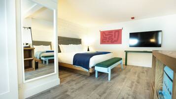 Ein Schlafzimmer mit einem Bett, einer Bank, einem Fernseher und einem Spiegel.