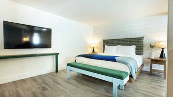 Un dormitorio con una cama, un banco, un televisor y dos lámparas.