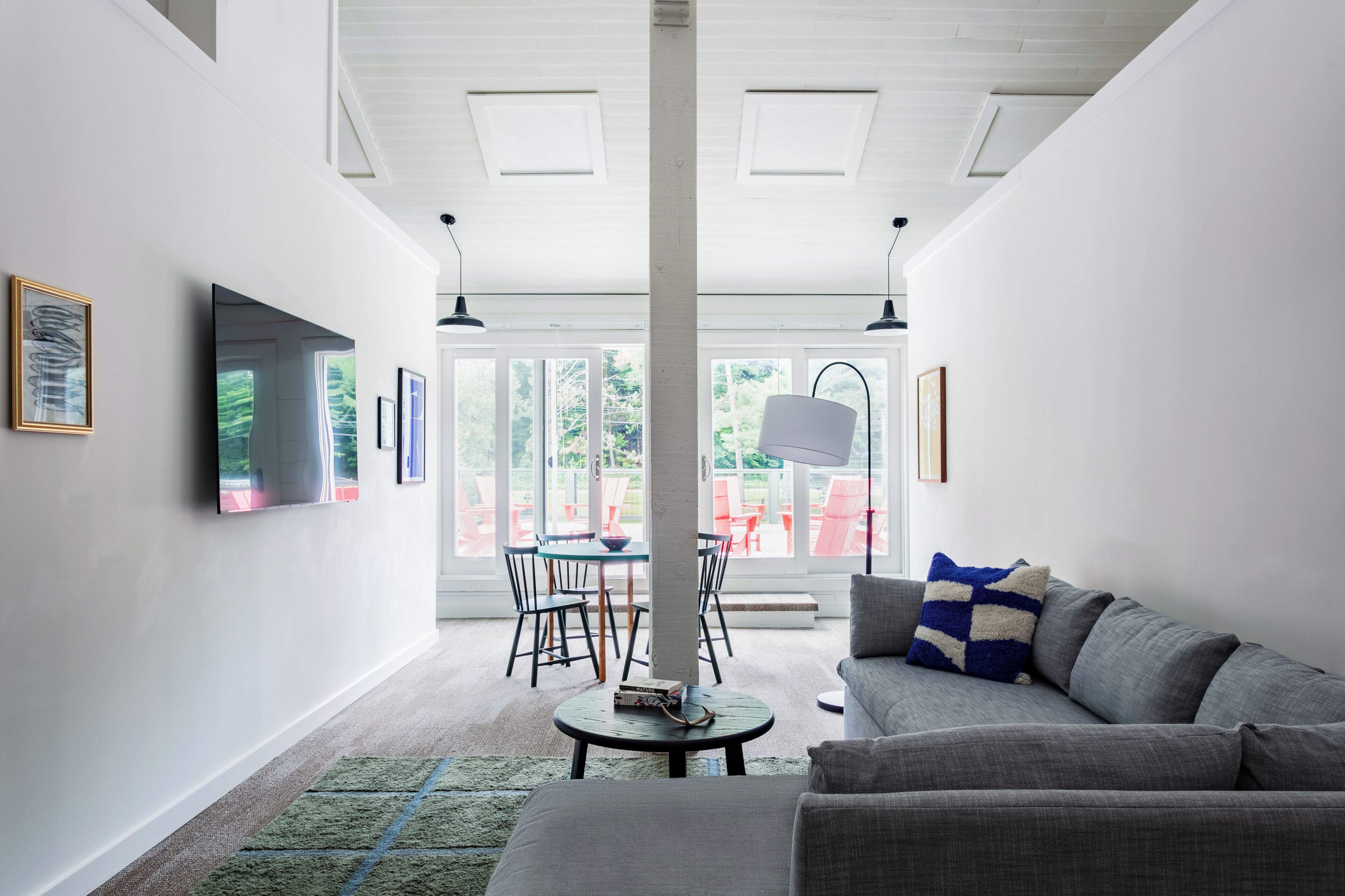 A modern living room with a gray sofa, a round coffee table, and a dining area with a table and chairs.