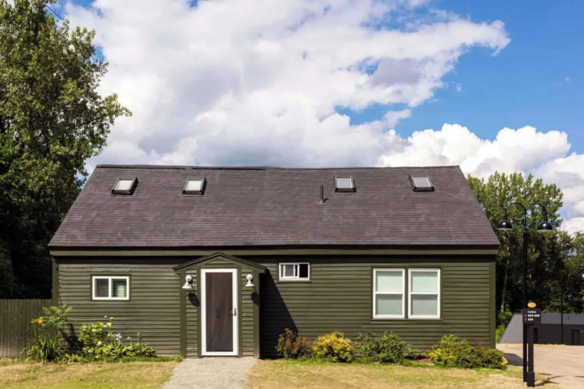 A single-story building with a dark green exterior, a front door, and a small porch.