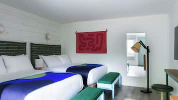 A hotel room with two beds, a desk, a chair, a lamp, and a large mirror.