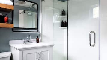 A modern bathroom with a glass shower enclosure, a white vanity, and a mirror above the sink.