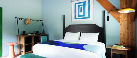 Un dormitorio con cama, mesita de noche, lámpara, un sombrero en la pared y un marco de fotos.