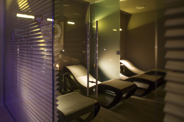 A modern room with a glass partition, a massage chair, and a small table. - Olivi Hotel & Natural Spa (Sirmione)