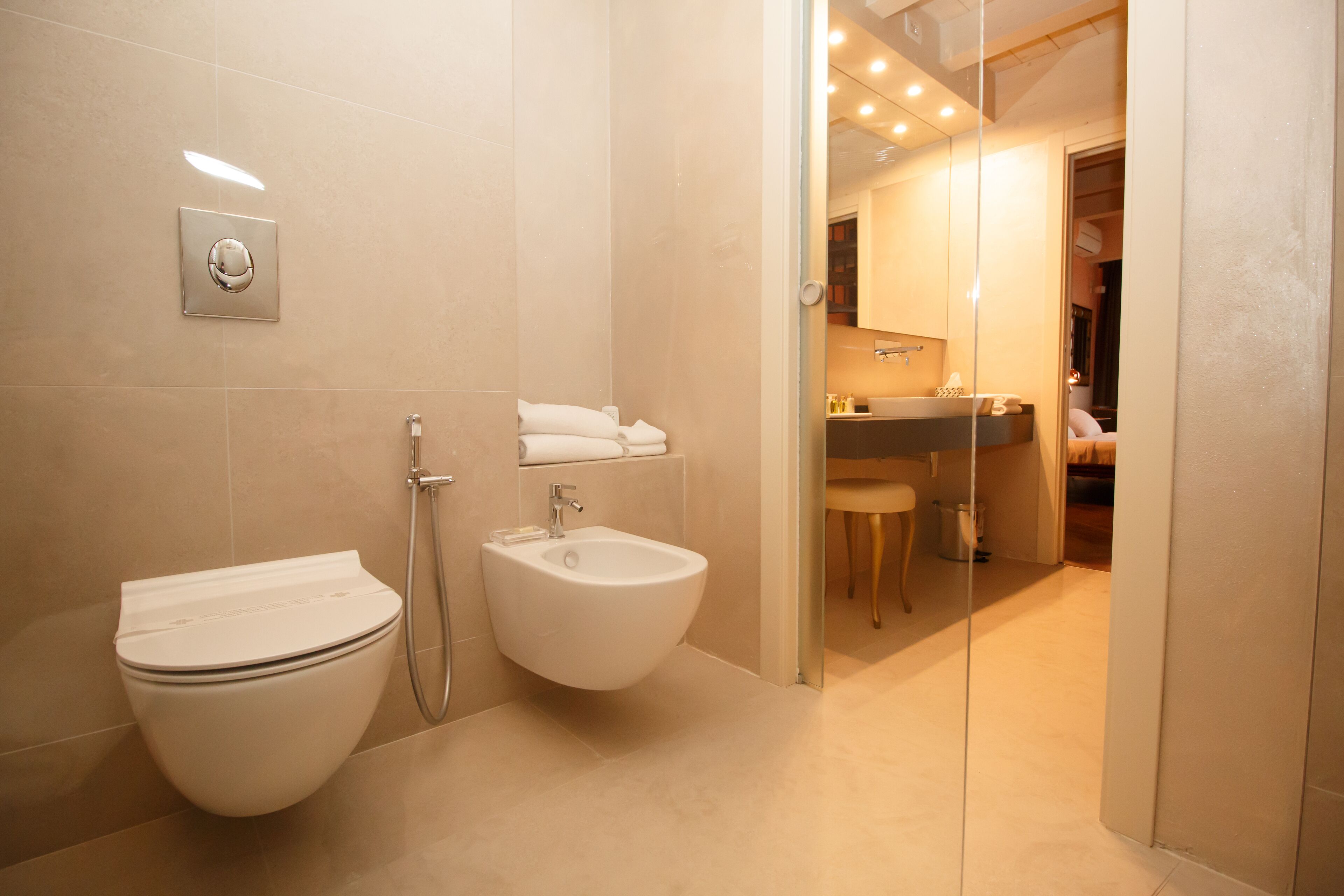 Une salle de bain moderne équipée de toilettes, d’un bidet et d’une douche séparée par une paroi en verre.