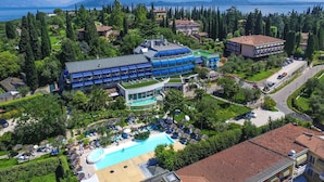 An aerial view of a resort with a swimming pool, multiple buildings, and a view of the lake. -  Olivi Hotel & Natural Spa (Sirmione)