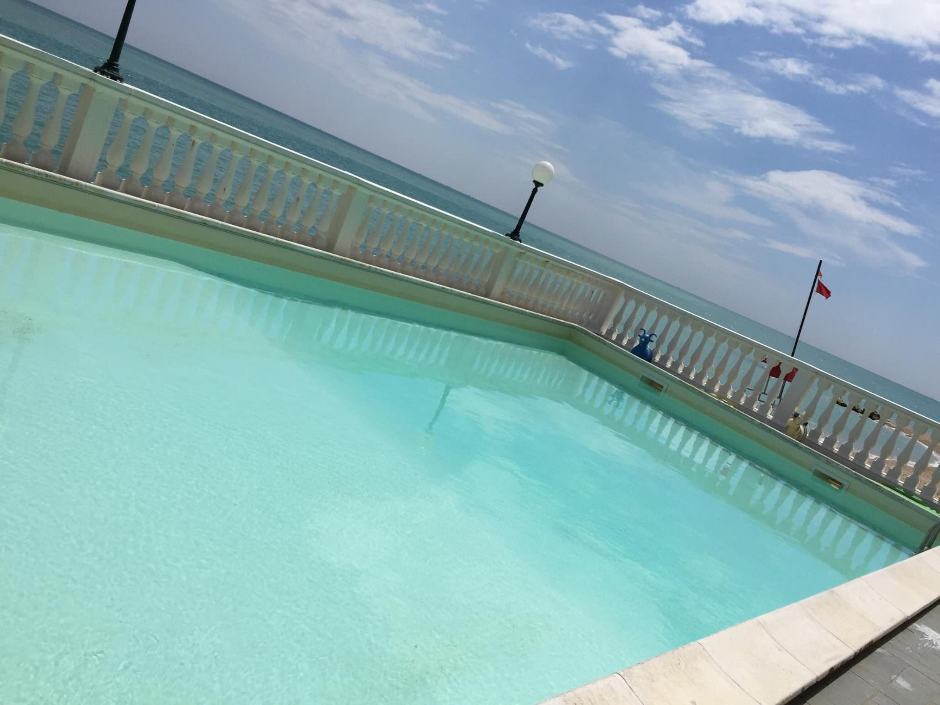 Une piscine offrant une vue dégagée sur la mer et dotée d’une balustrade blanche.