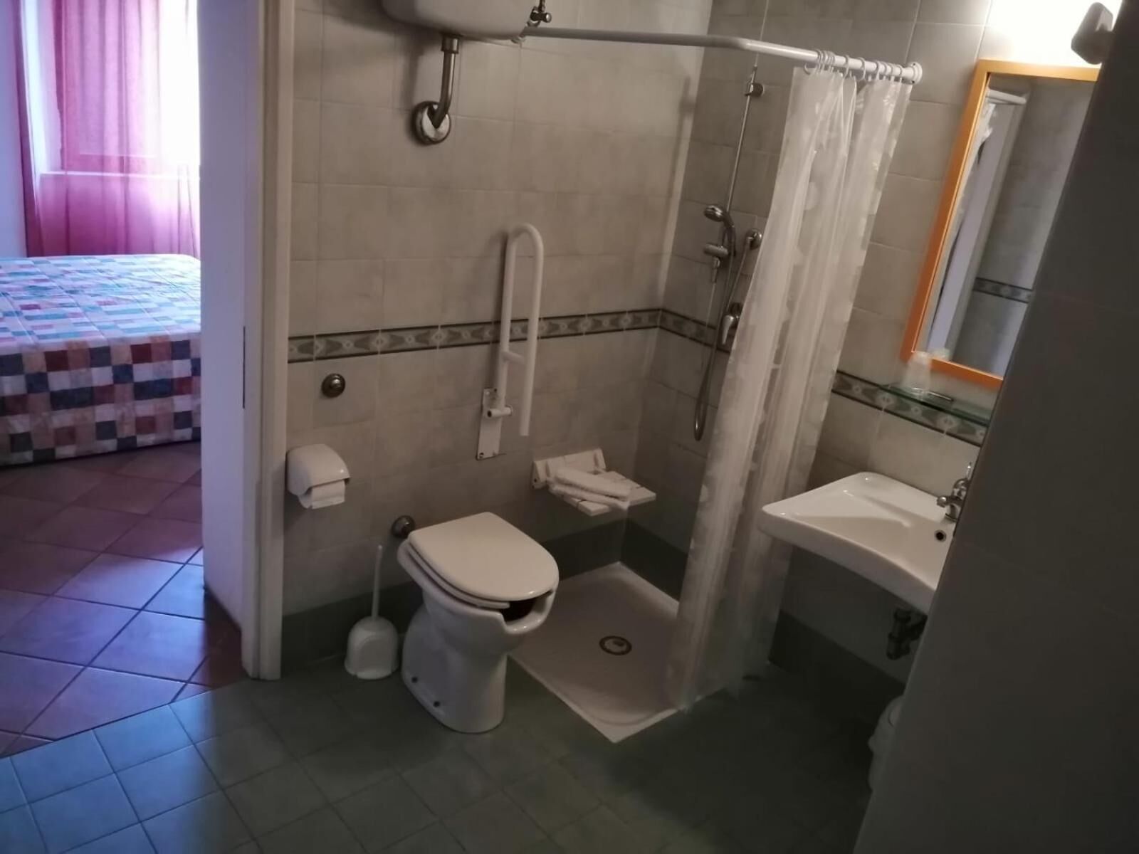 A bathroom with a toilet, shower, and sink.