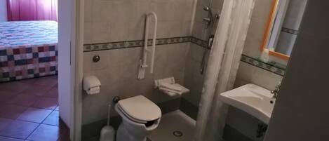 A bathroom with a toilet, shower, and sink.