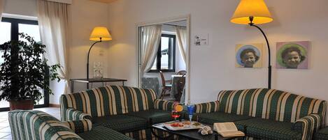 A living room with striped sofas, a table with drinks and snacks, a potted plant, and two lamps.