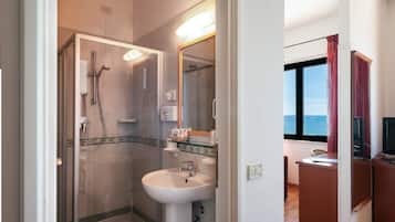 Un baño moderno con ducha de vidrio, lavamanos blanco y tocador con espejo.