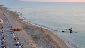 Una playa con filas de sillas de playa y una torre de salvavidas.