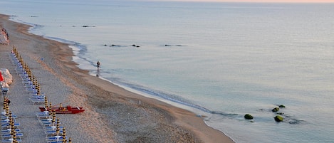 Een privéstrand, ligstoelen aan het strand, parasols