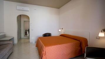 A hotel room with a bed, a chair, a desk, and a staircase leading to another room.