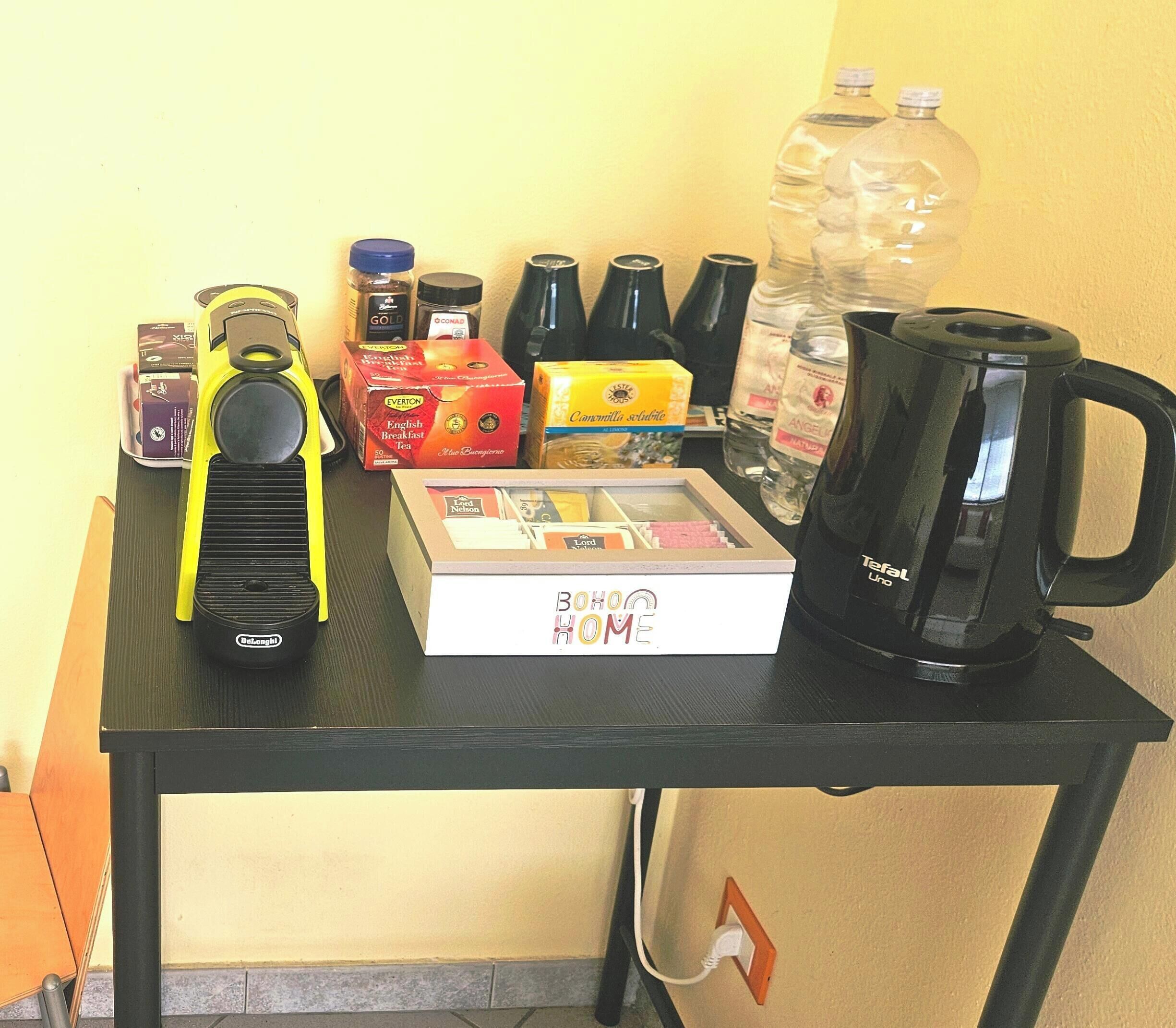 A table with various items including a coffee maker, tea boxes, condiments, and a water bottle.