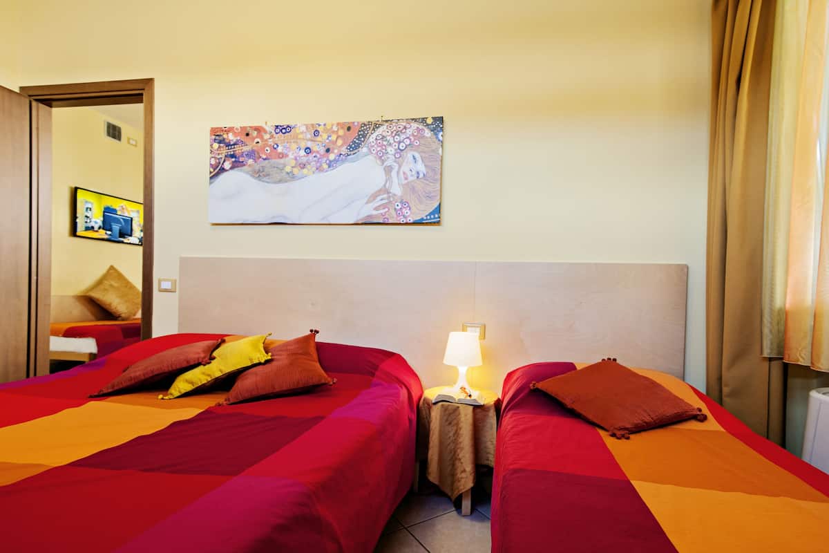 Une chambre d’hôtel avec deux lits, un tableau au mur et une table de chevet avec une lampe.