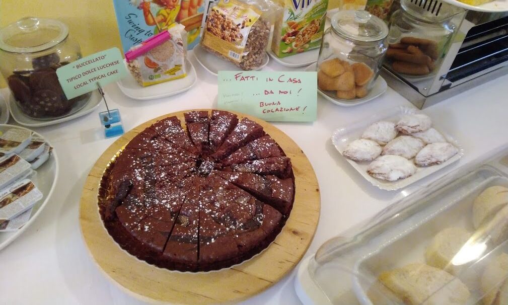 Een desserttafel met chocoladetaart, cantuccini en andere gebakjes.
